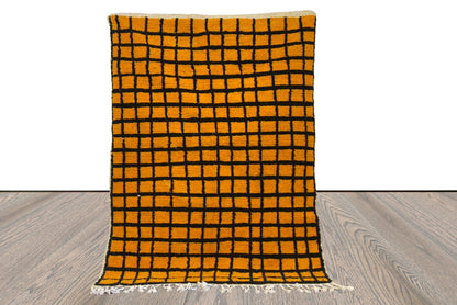 Tapis marocain tissé à la main jaune et noir quadrillé.